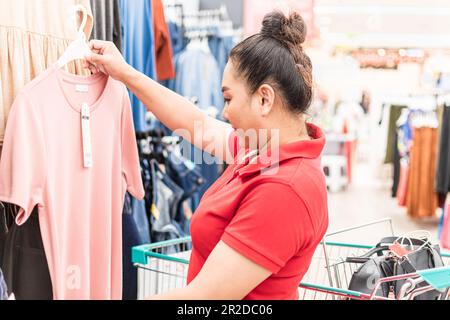 Beautiful young women smiling while choosing clothes for her special day In Women's apparel department of supermarket on casual day, Concept for shopp Stock Photo