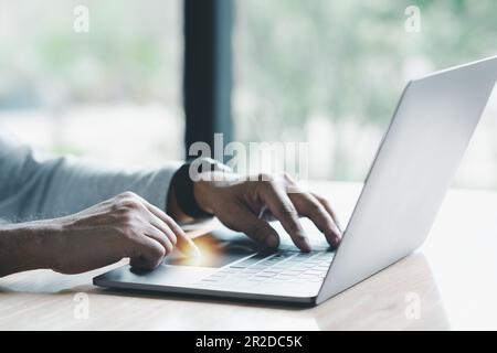 Man uses his finger to press button to turn off, closed, shut down laptop computer placed on desk, is time to finish each day before going home for sa Stock Photo