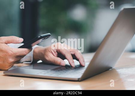 Man uses his finger to press button to turn off, closed, shut down laptop computer placed on desk, is time to finish each day before going home for sa Stock Photo