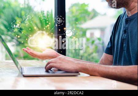 businessman uses a smartphone and laptop with a cloud computing diagram display on a virtual screen. Cloud technology. Data storage. Networking server Stock Photo