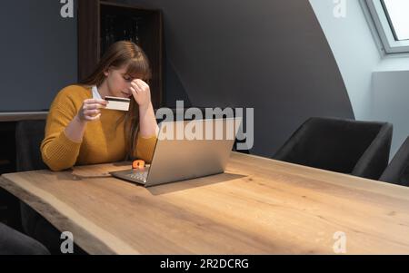 Stolen information in payment process. Confused female hold plastic bank credit card unable to enter billing account website. Disappointed woman clien Stock Photo