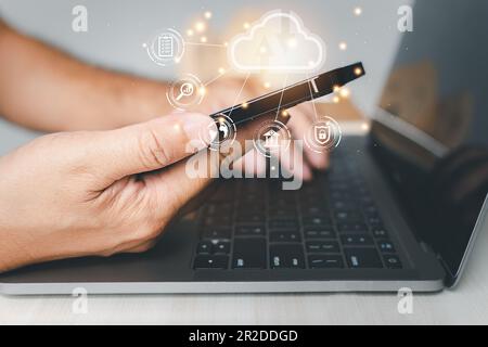 Admin man uses a smartphone and laptop with a cloud computing diagram display on a virtual screen. Cloud technology. Data storage. Networking server a Stock Photo