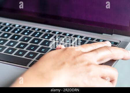 After clicking saving all business work use your finger to press the button to turn it off closed the gray laptop computer, placed it on a table, is t Stock Photo