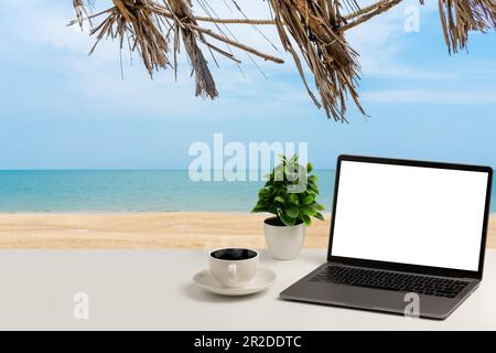 A blank white screen laptop, coffee cup, and vase are placed on a white desk outdoor. concept for business, technology, internet, design, and programm Stock Photo