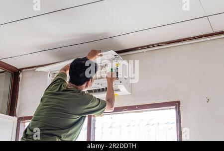A single man is working indoor in the building. The technician is installing the air conditioner in the bedroom summer. Close up, Selective focus. Blu Stock Photo