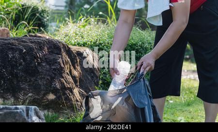 A woman cleans up by picking up plastic bottles at a natural water reservoir. Concept of protecting the environment, saving the world, recycling, redu Stock Photo