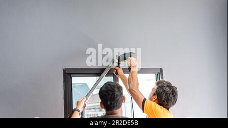 Two technicians are drilling a wall to install an air conditioner in a bedroom during the summer. man working in a building. close-up. selective focus Stock Photo