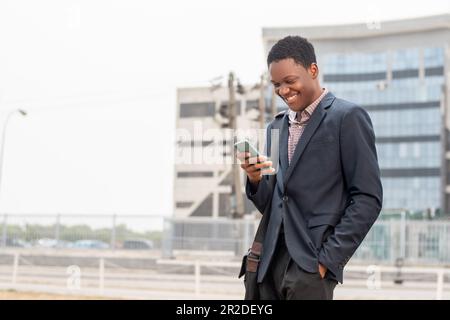 young african businessman smiling while using phone Stock Photo