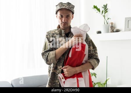 partial view of man in military uniform holding canada national flag. Stock Photo