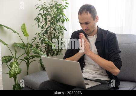 Young man showing gesture in sign language using laptop, make video call Stock Photo