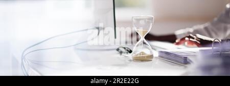 Late Invoice And Billing Deadline With Hourglass At Desk Stock Photo