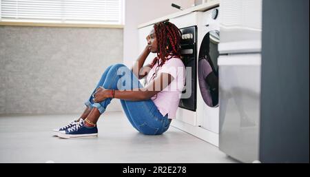 Frustrated Young Woman Sitting On Kitchen Floor Stock Photo