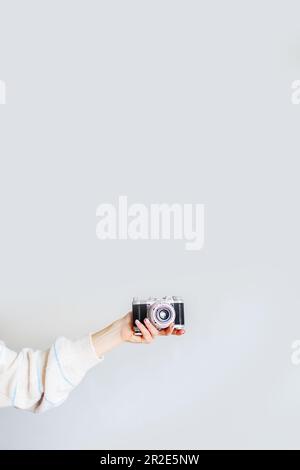 Woman's hand holds an old film camera on a white background. Stock Photo