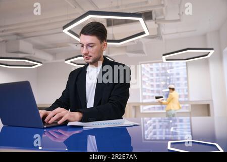 Young man working with graphs and data on laptop Stock Photo