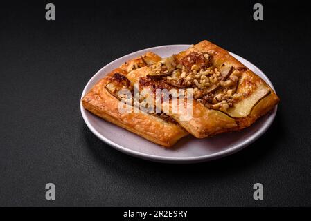 Delicious fresh sweet pie or pizza with pear, brie cheese, honey and nuts on a dark concrete background Stock Photo