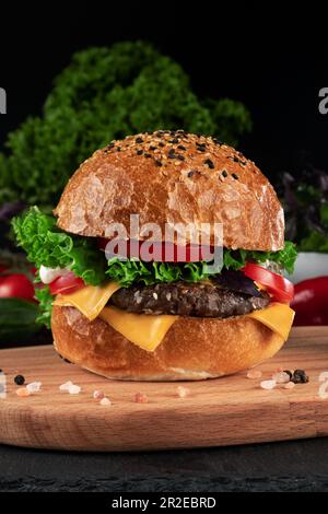 Hamburger with beef patty and fresh vegetables on a black background. Stock Photo