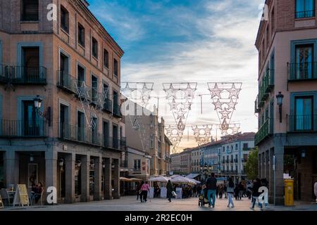 View of Plaza Azoguejo in the center of the city. Sunset colours. People enjoying tine outdoor on the street of Segovia at bars and restaurants. Stock Photo