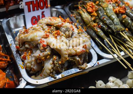 Many snacks and seafood in vietnamese night market with signs with vietnamese text 'time, price' translation Stock Photo