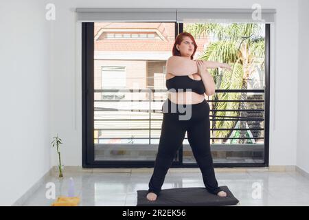 Overweight young black lady doing abs exercises, standing in