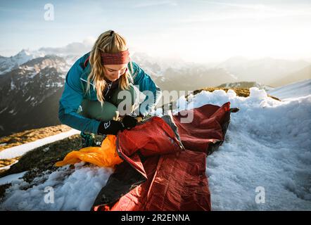 Young woman spreads her sleeping pad in the snow, Hinterriss, Karwendel, Tyrol, Austria Stock Photo