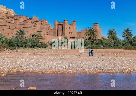 Two local women walk in front of the city of Ait Ben Haddou, Morocco Stock Photo