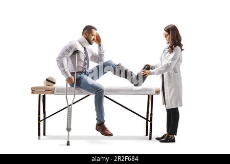 Female doctor putting on a walking brace to a male patient isolated on white background Stock Photo