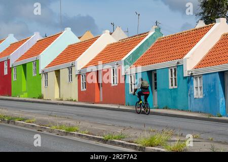A cyclist passes a row of colorful houses, Pietermaai neighborhood, Willemstad, Curacao, Netherlands Antilles, Caribbean Stock Photo