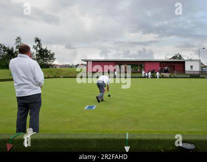 Bowls in play in front of the red pavilion clubhouse at the Balornock lawn bowling green in Glasgow, Scotland, UK Stock Photo
