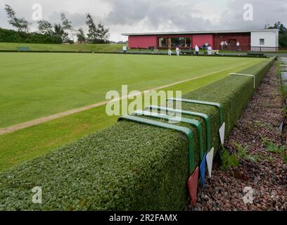 Bowls in play in front of flags at the red pavilion clubhouse at the Balornock lawn bowling green in Glasgow, Scotland, UK Stock Photo