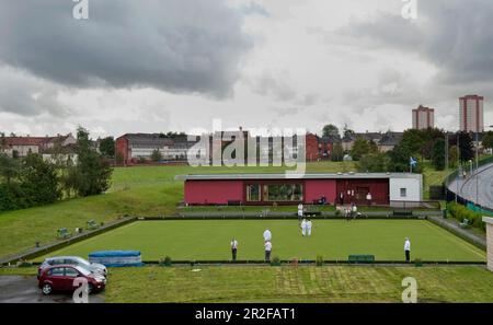 Bowls in play within the urban enivornment in front of the red pavilion clubhouse at the Balornock lawn bowling green in Glasgow, Scotland, UK Stock Photo