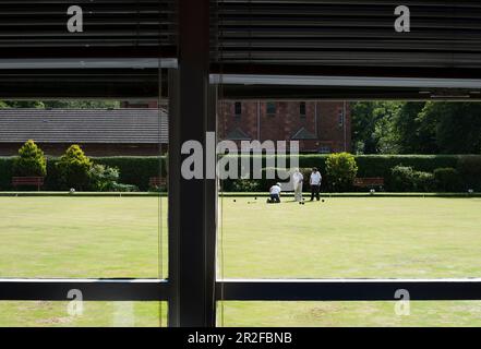 A view of women playing bowls from the interior of the club house at the Kilmarnock lawn bowling green in Kilmarnock, Ayrshire, Scotland, UK Stock Photo