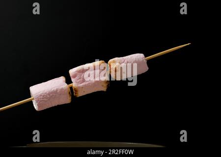 Roasted marshmallows on a skewer isolated on black background and copy space Stock Photo