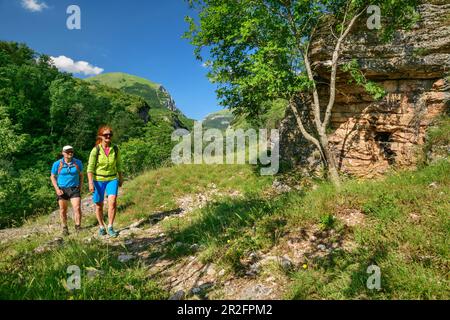 Man and woman hiking past rock face, Grande Anello dei Sibillini, Sibillini Mountains, Monti Sibillini, National Park Monti Sibillini, Parco nazionale Stock Photo