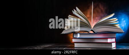 A composition with an open book lying on a stack of other books Stock Photo
