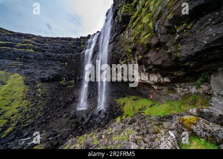 Tourist at the Fossa Waterfall on island Bordoy in the Faroe Islands ...