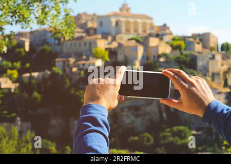 Hand holding mobile phone taking picture of Gordes village, one of the most beautiful villages in France Stock Photo