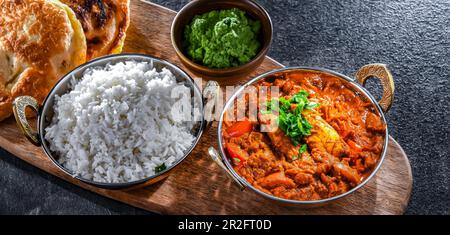 Butter chicken with rice and naan flatbread served in original indian karahi pots Stock Photo