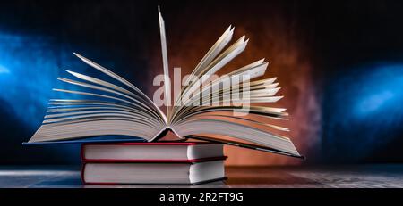 A composition with an open book lying on a stack of other books Stock Photo