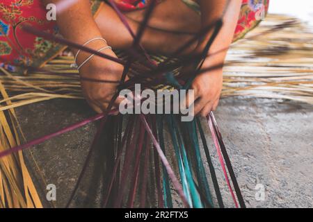 Selective focus on woman's hands weaving a krajood mat, Natural products from Taley Noi, Pattalung, Thailand Stock Photo