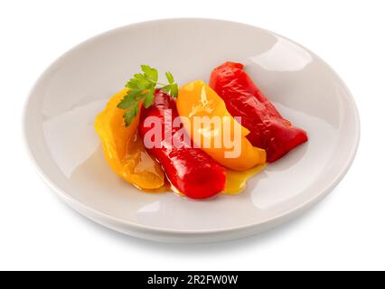 Slices of cooked yellow and red peppers seasoned with olive oil and parsley leaves in white dish isolated on white with clipping path Stock Photo
