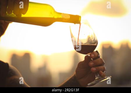 Glass and bottle of red wine in selective focus on glass of wine. pouring red wine at sunset Stock Photo