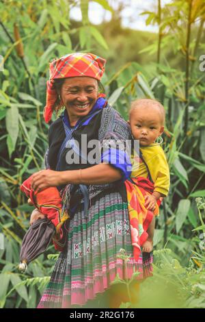 Mu cang chai, Vietnam-August 27, 2018: Smling Hmong tribe woman carrying her child in her backpack in Mu cang chai Northern Vietnam Stock Photo