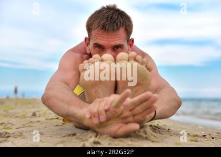 Young man practicing yoga on beach, close up Stock Photo