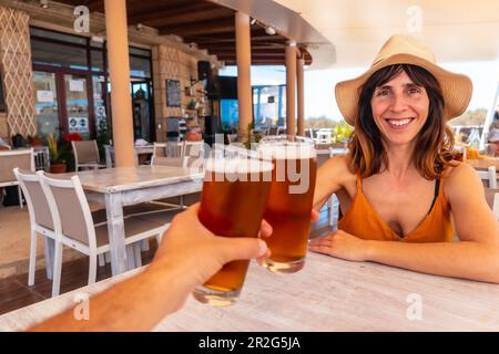 Date with the girlfriend toasting with beer in a restaurant on a summer sunset Stock Photo