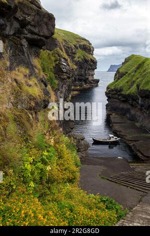 Looking down into small port of Gjogv. Stairs in the foreground, fishing boat. Eysturoy, Faroe Islands. Stock Photo