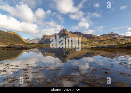 Mountains and sky are reflected in the fjord. Small house. Flakstad, Lofoten, Nordland, Norway Stock Photo