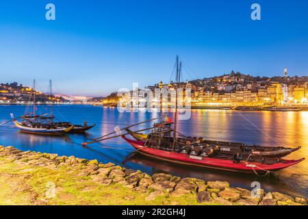 Barcos Rabelos, port wine boats on the Duero River in front of the historic old town of Porto at night, Portugal Stock Photo