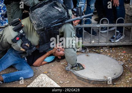 Jerusalem, Israel. 18th May, 2023. An Israeli border police officer detains a right wing youth outside Damascus gate In Jerusalem during the flag march. Tens of thousands of young religious-Zionist men and women marched through the capital waving Star of David flags into the Old City of Jerusalem, as part of a controversial flag march, marking the reunification of the city during the Six Day War and Israel's capture of the Temple Mount and the Western Wall, Judaism's holiest sites. Credit: SOPA Images Limited/Alamy Live News Stock Photo