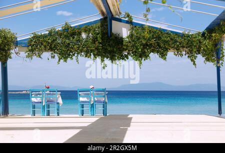 Kokkari, two lonely restaurant tables between the taverns at the port overlooking the sea on the island of Samos in Greece Stock Photo