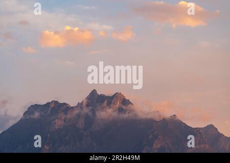 The peaks of Pilatus-Kulm in clouds with red sky Stock Photo